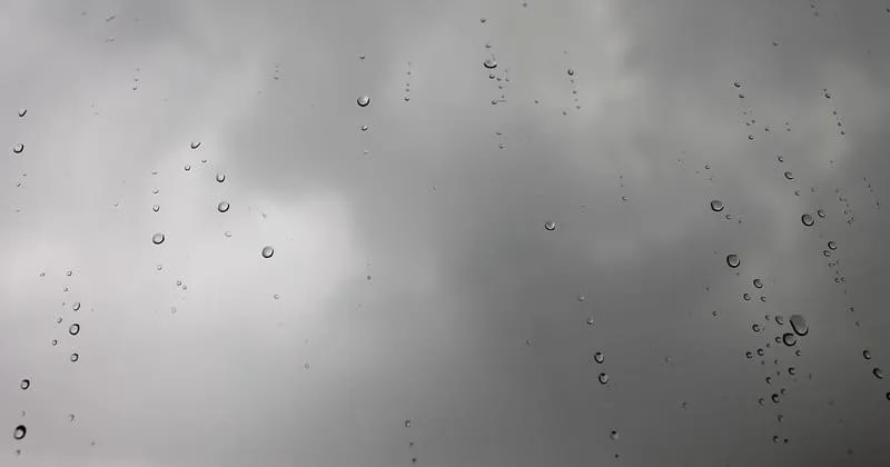 雨粒が付いた窓ガラス越しの灰色の空