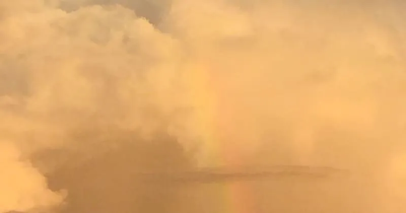 夕空に立ち上がる雲の壁と淡い虹