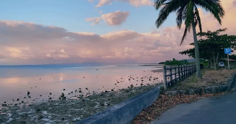 石垣島の海沿いの歩道。夕暮れの空と雨上がりの路面の反射が見える。