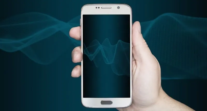 青い背景を背に、スマートフォンを手に持つ人物の写真