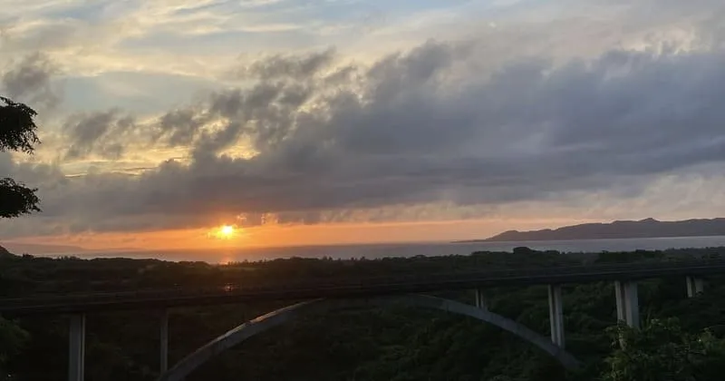 夕焼け空の下でアーチ橋と森が横に伸びる石垣島の風景