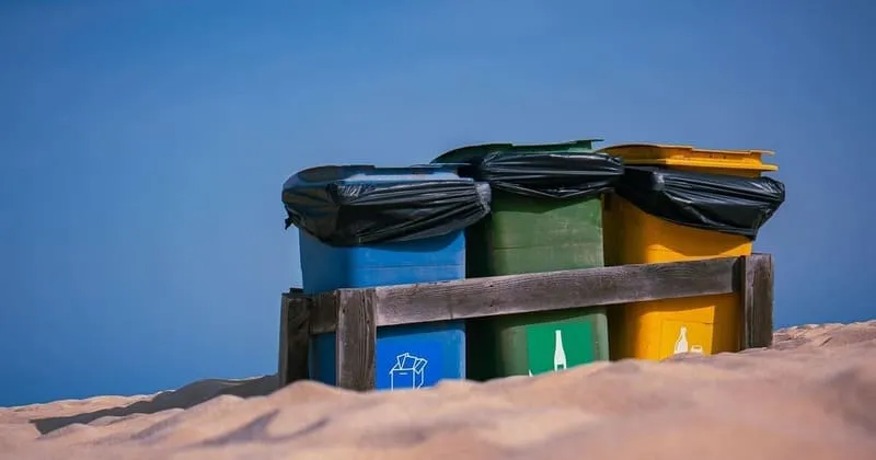 青空の下 砂地に並ぶ色分けごみ箱