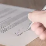 契約書に署名する手元を近接で写す