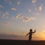 夕焼け空に遊ぶ幼児のシルエット