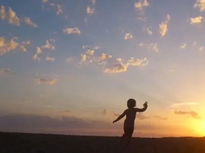 夕焼け空に遊ぶ幼児のシルエット