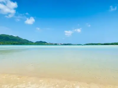 浅瀬の砂浜と静かな海、遠くに低い山並み