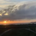 夕焼け空の下、森の上にアーチ橋と海が見える石垣島の風景