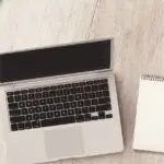 丸テーブルにノートPCとメモ帳とスマホを置いた作業机