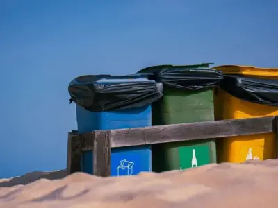 青空の下 砂地に並ぶ色分けごみ箱