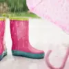 雨の日の濡れた地面に並ぶ子ども用長靴と傘