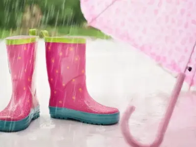 雨の日の濡れた地面に並ぶ子ども用長靴と傘