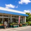 南国の街並みにある商店の店先に野菜が並ぶ買い物風景